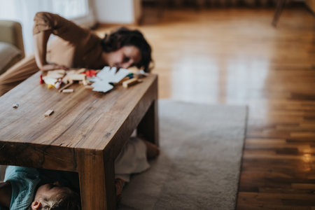 Mother and child playing hide and seek under table at homeの写真素材