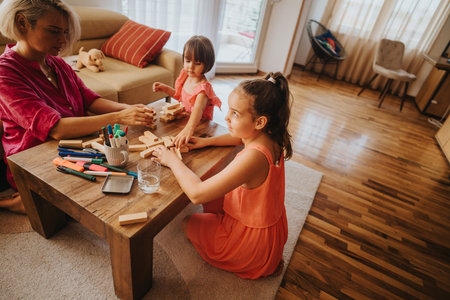 Mother and daughters playing with blocks at home in living roomの写真素材