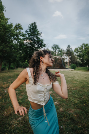 Happy young girl dancing freely in a lush green parkの写真素材