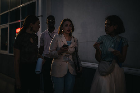 Group of young adults engaged in conversation while walking together on an urban street at night, illuminated by ambient city lightsの写真素材