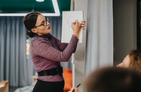 Teacher demonstrating drawing technique to engaged students in classroom settingの写真素材