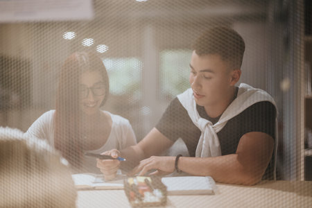 Students collaborating on project in library setting through windowの写真素材
