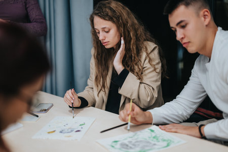 Students engaged in a creative art class painting togetherの写真素材