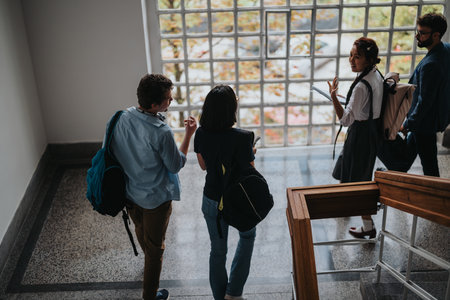 Students consulting professor in university hallway with backpacksの写真素材