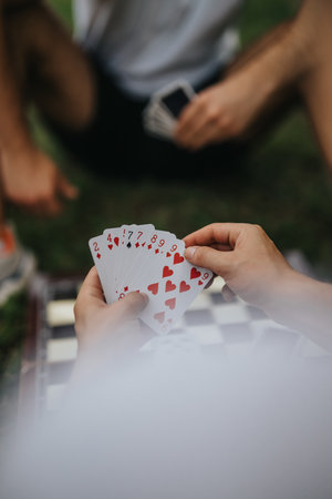 Friends playing cards outdoors during a relaxing summer afternoonの写真素材