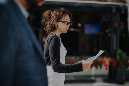 Young woman reading a document while walking outdoorsの写真素材