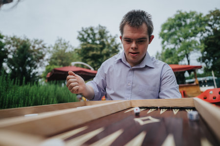Boy with Down syndrome playing backgammon outside in parkの写真素材