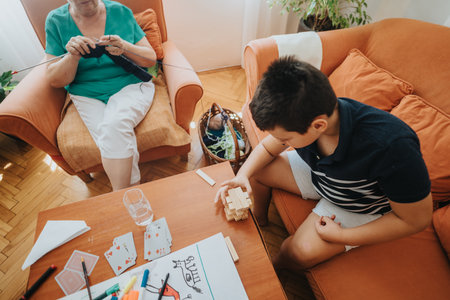 Grandmother knitting while grandson plays with building blocks at homeの写真素材