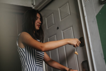 Young woman unlocking a door with optimism and anticipationの写真素材
