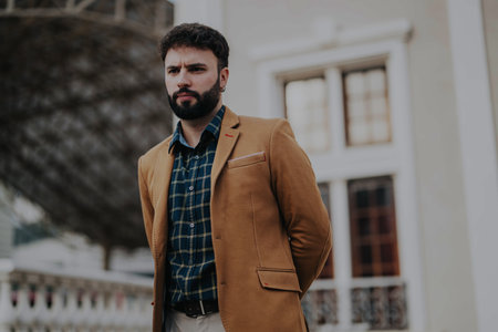 Confident businessman posing outdoors in a stylish brown suit jacket