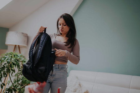 Young student organizing backpack in cozy modern living room