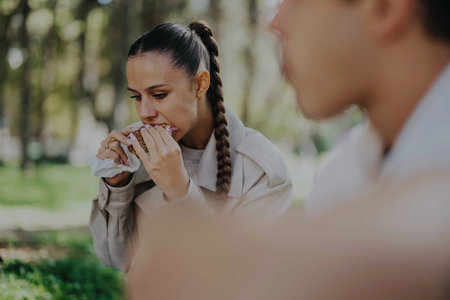 Young students enjoying lunch in a sunny park settingの写真素材