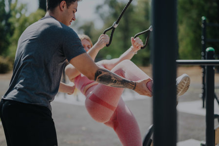 Friends enjoying an outdoor workout session together in a park setting with supportive coaching and...