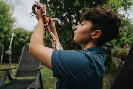 Young girl interacting with snakes in a lush garden settingの写真素材