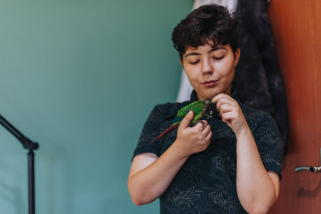 Young woman gently holding and interacting with a parrot