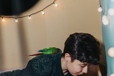 Young woman with a parrot indoors surrounded by string lightsの写真素材