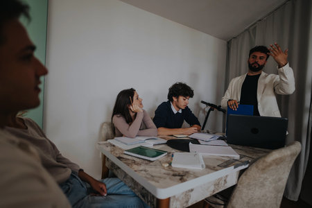 High school students collaborating on a school project with their professor in a cozy home setting, surrounded by notebooks and a laptop.の写真素材