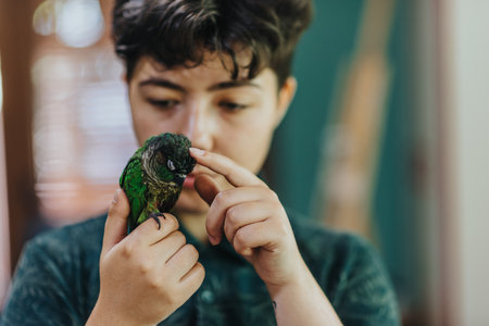 Young girl gently interacting with a pet parrot at homeの写真素材