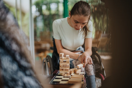 Boy with Down syndrome, girl in wheelchair, and elderly woman playing blocksの写真素材