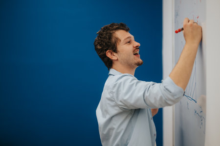 Young teacher enthusiastically explaining concepts on a whiteboardの写真素材