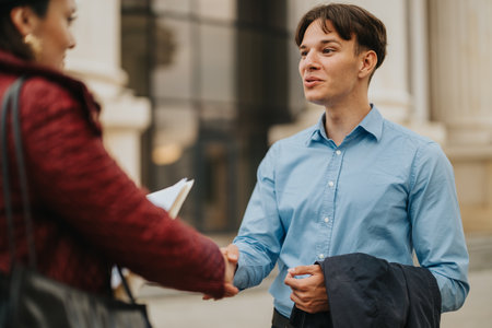 Young professionals greeting with a handshake outside modern buildingの写真素材