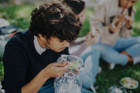 Group of students enjoying lunch together in a sunny parkの写真素材