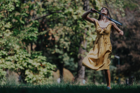 Woman playing badminton outdoors in a sunny green park