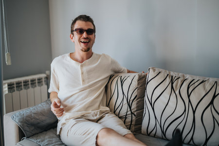 Young man relaxing on a sofa with a joyful expressionの写真素材