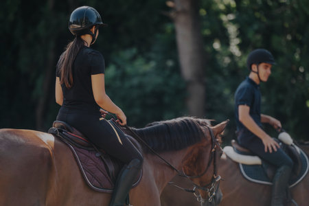 Young riders enjoying a sunny day of horseback riding in natureの写真素材