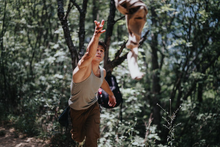 Young man hiking in forest and throwing shirt on sunny summer dayの写真素材