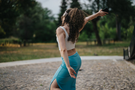 Young woman performing joyful dance in a sunny park settingの写真素材