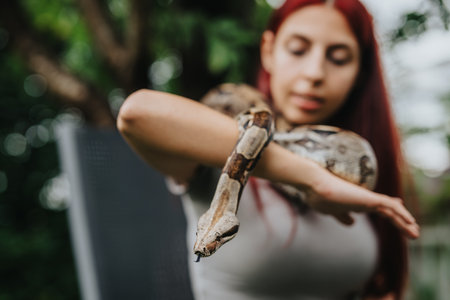 Girl holding a snake on her arm in a natural setting