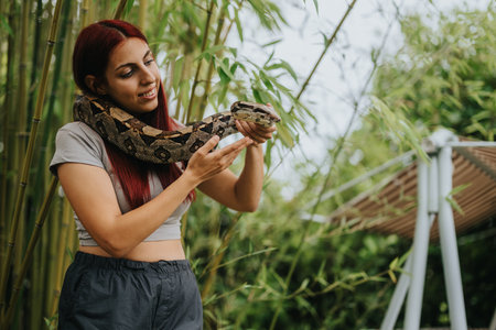 Girl holding a snake in a serene outdoor settingの写真素材