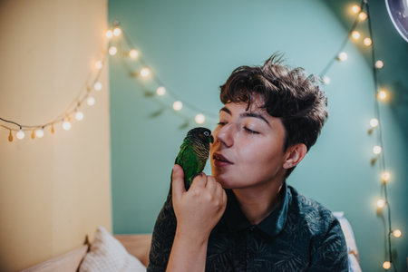 Young person enjoying a moment with their pet parrot at homeの写真素材