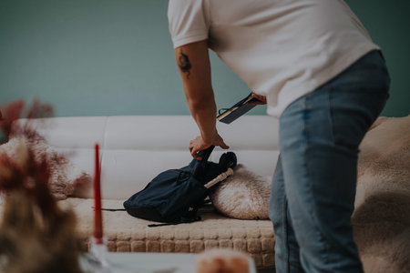 Person preparing a backpack in a cozy living room setting