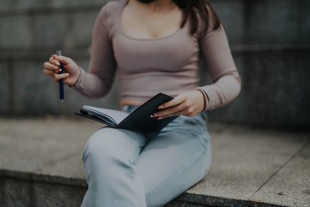 Young female student studying on city steps after school classesの写真素材
