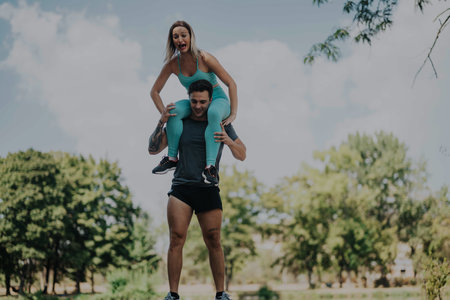 Joyful friends engaging in playful workout activities at a park on a sunny day, showcasing teamwork, strength, and enthusiasm.の写真素材