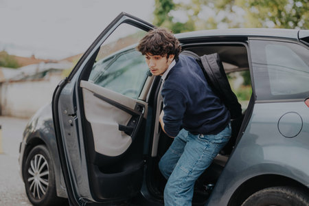 Teenage boy stepping out of car on way to school drop-offの写真素材