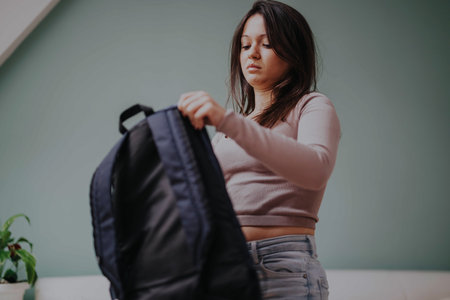 Young student packing backpack for school or travel preparationの写真素材