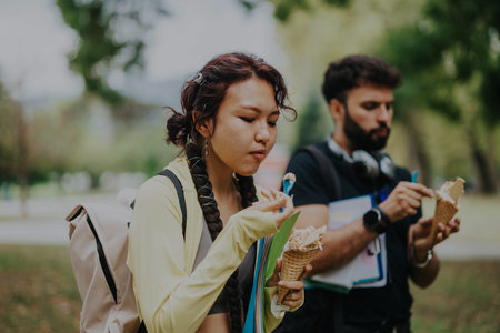 Multicultural students enjoying ice cream during break in parkの写真素材