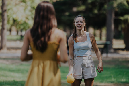 Two friends playing ball in a sunny park settingの写真素材