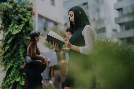 Business professionals discussing strategy outdoors with booksの写真素材