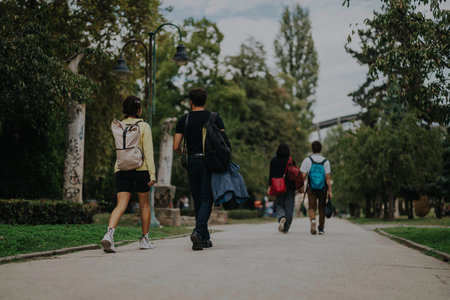 Group of friends walking together in a lush green park areaの写真素材