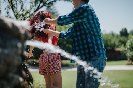 Group of friends having fun at a sunny park fountain, enjoying summerの写真素材