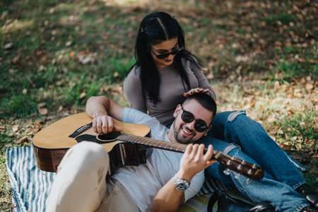 Couple enjoying a relaxing afternoon with guitar in the park