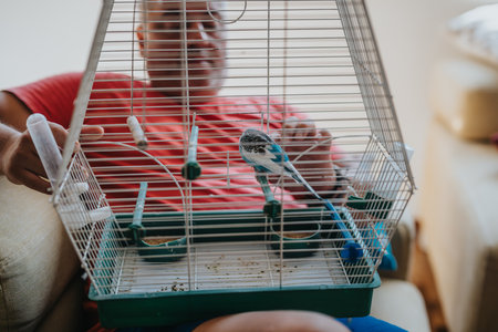 Man enjoying quality time with pet budgie in a cageの写真素材