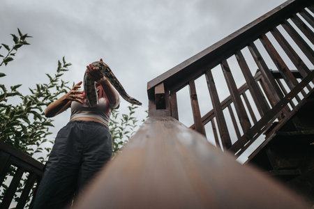 Person holding snake outdoors on wooden staircase