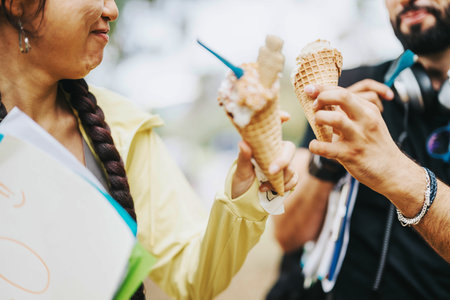 Multicultural students enjoying ice cream cones in park during breakの写真素材