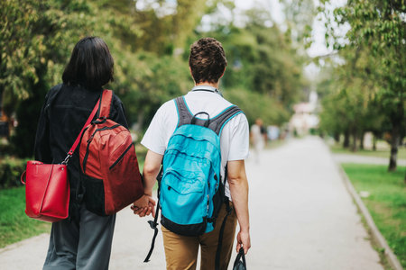 Couple strolling hand in hand through a scenic park pathの写真素材