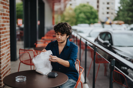 Young man enjoying outdoor dining at a trendy cafe terrace